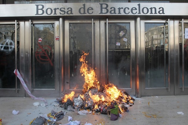 A pile of garbage on fire in front of the Barcelona stock exchange